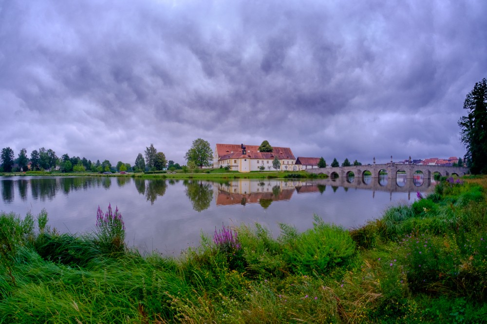 Lake reflecting a colonial building under a stormy sky