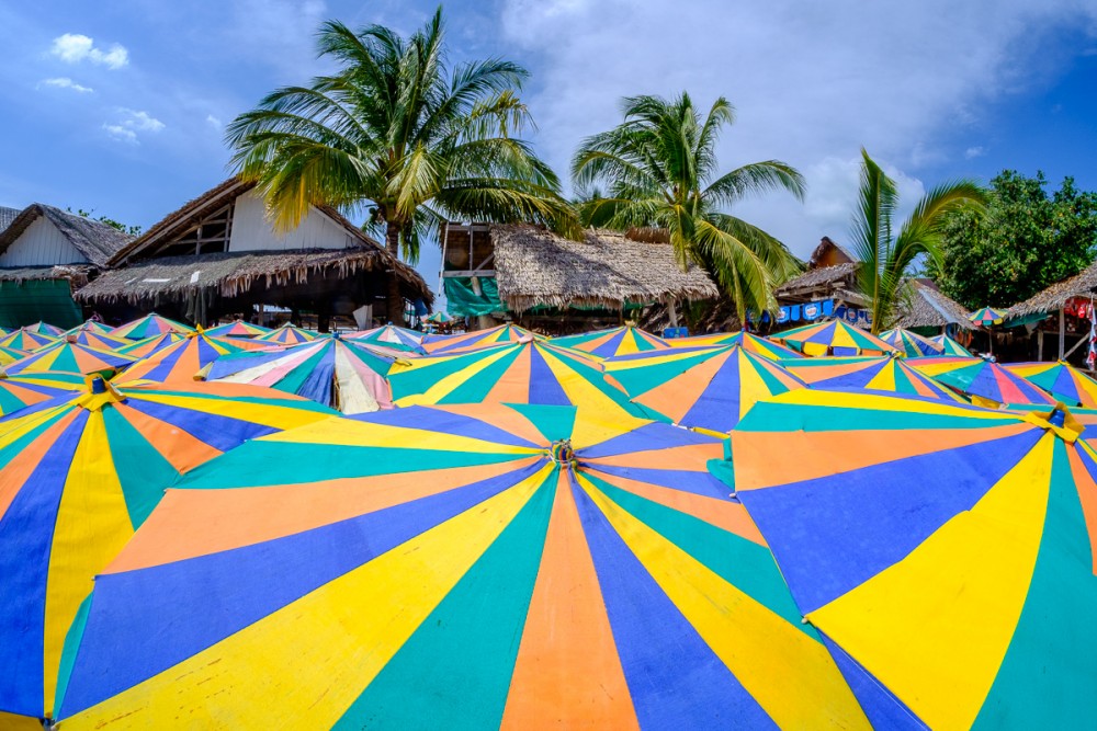 Colorful beach umbrellas and palm trees on a tropical beach, Samyang 8mm fisheye