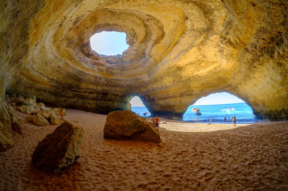 Inside the Benagil Sea Cave: a sandy beach under the round skylight in the cave roof